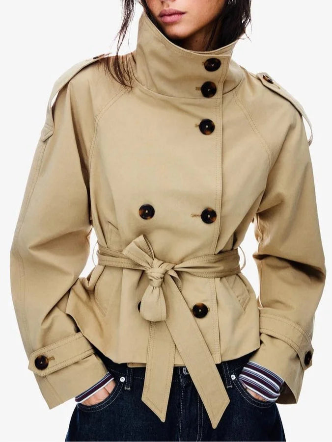 trench coat for women with a structured fit, high collar and dark buttons. Crafted from premium fabric, it highlights the waist and adds refined elegance to any autumn or winter outfit.