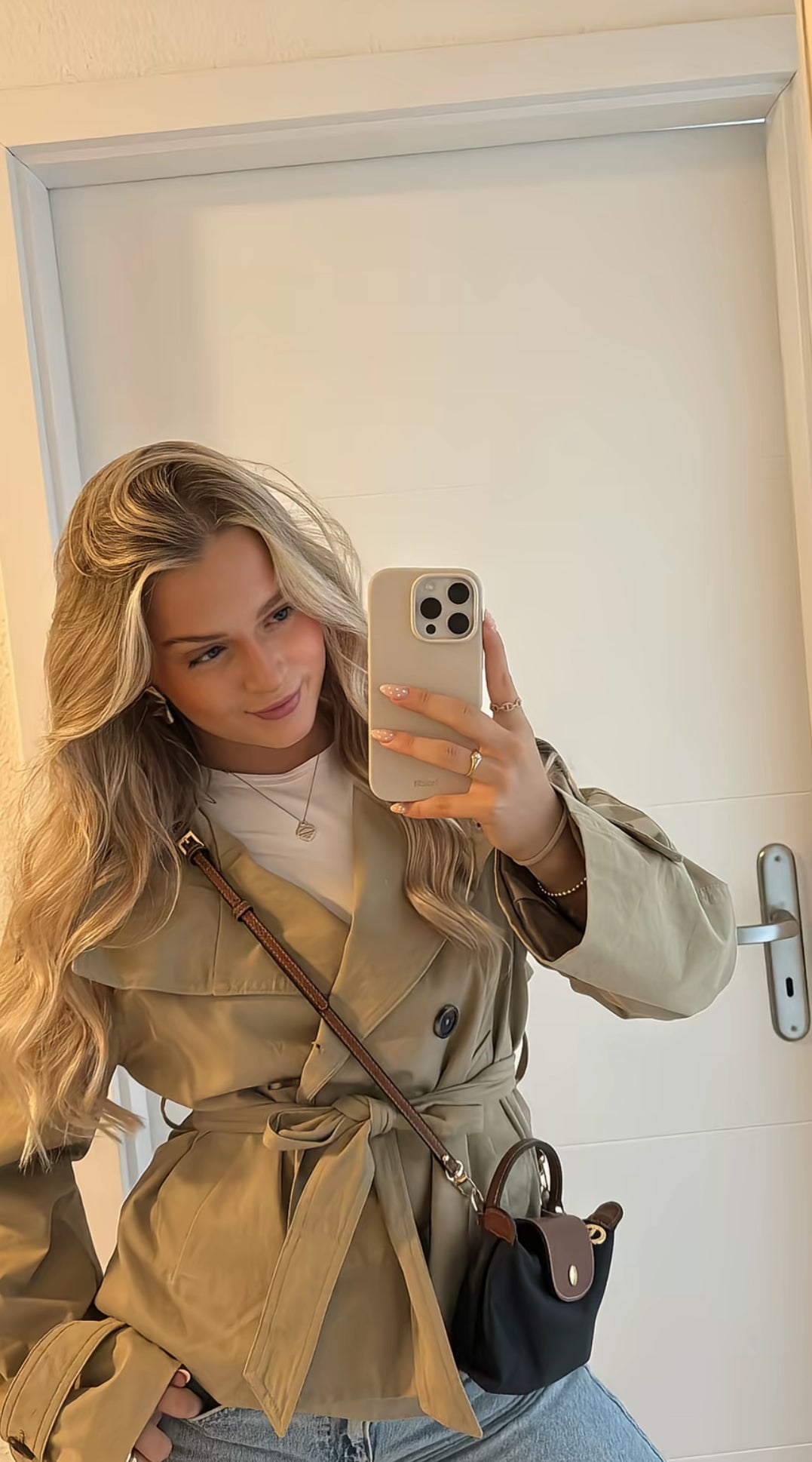 trench coat for women with a structured fit, high collar and dark buttons. Crafted from premium fabric, it highlights the waist and adds refined elegance to any autumn or winter outfit.