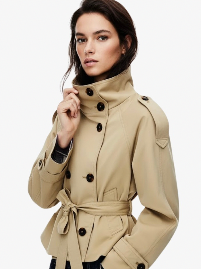trench coat for women with a structured fit, high collar and dark buttons. Crafted from premium fabric, it highlights the waist and adds refined elegance to any autumn or winter outfit.