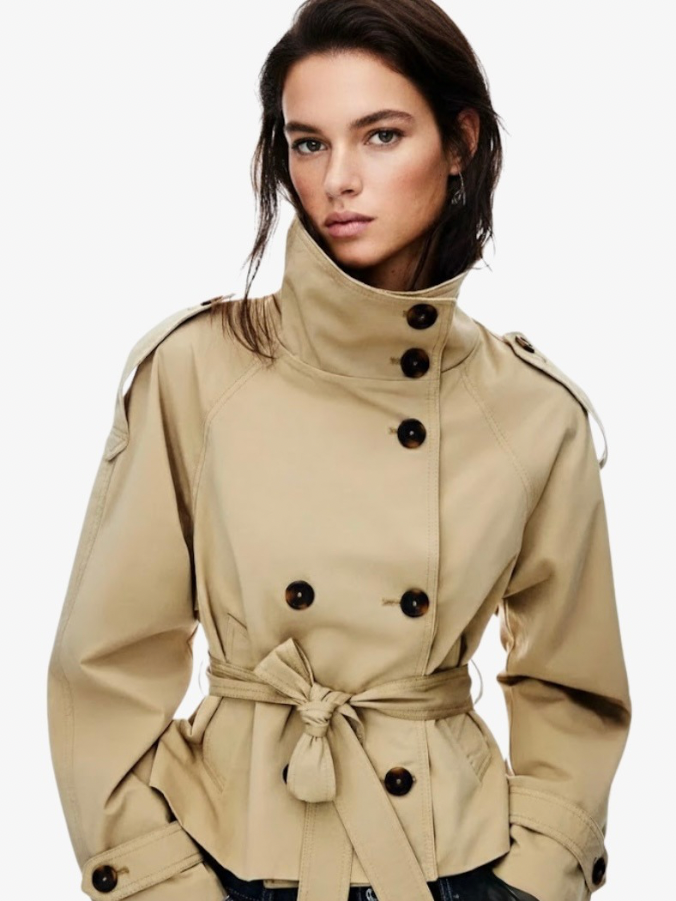trench coat for women with a structured fit, high collar and dark buttons. Crafted from premium fabric, it highlights the waist and adds refined elegance to any autumn or winter outfit.