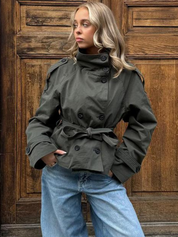 trench coat for women with a structured fit, high collar and dark buttons. Crafted from premium fabric, it highlights the waist and adds refined elegance to any autumn or winter outfit.