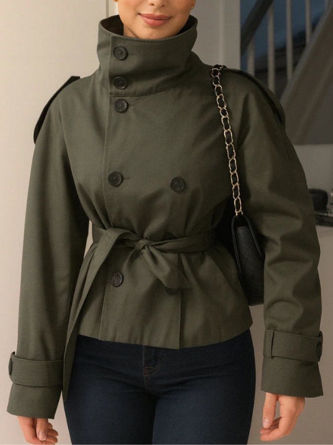 trench coat for women with a structured fit, high collar and dark buttons. Crafted from premium fabric, it highlights the waist and adds refined elegance to any autumn or winter outfit.