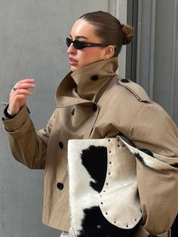 trench coat for women with a structured fit, high collar and dark buttons. Crafted from premium fabric, it highlights the waist and adds refined elegance to any autumn or winter outfit.