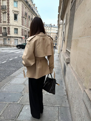 trench coat for women with a structured fit, high collar and dark buttons. Crafted from premium fabric, it highlights the waist and adds refined elegance to any autumn or winter outfit.