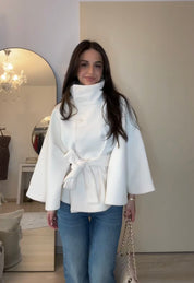 High-Neck Belted Cape Jacket in camel wool blend. Poncho-inspired autumn/winter coat with high-neck collar, cape silhouette and adjustable waist belt. A chic belted jacket combining elegance, comfort and versatile seasonal style.