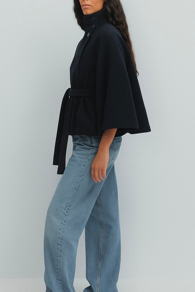 High-Neck Belted Cape Jacket in camel wool blend. Poncho-inspired autumn/winter coat with high-neck collar, cape silhouette and adjustable waist belt. A chic belted jacket combining elegance, comfort and versatile seasonal style.