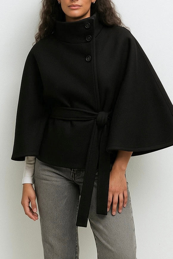 High-Neck Belted Cape Jacket in camel wool blend. Poncho-inspired autumn/winter coat with high-neck collar, cape silhouette and adjustable waist belt. A chic belted jacket combining elegance, comfort and versatile seasonal style.