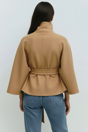 High-Neck Belted Cape Jacket in camel wool blend. Poncho-inspired autumn/winter coat with high-neck collar, cape silhouette and adjustable waist belt. A chic belted jacket combining elegance, comfort and versatile seasonal style.