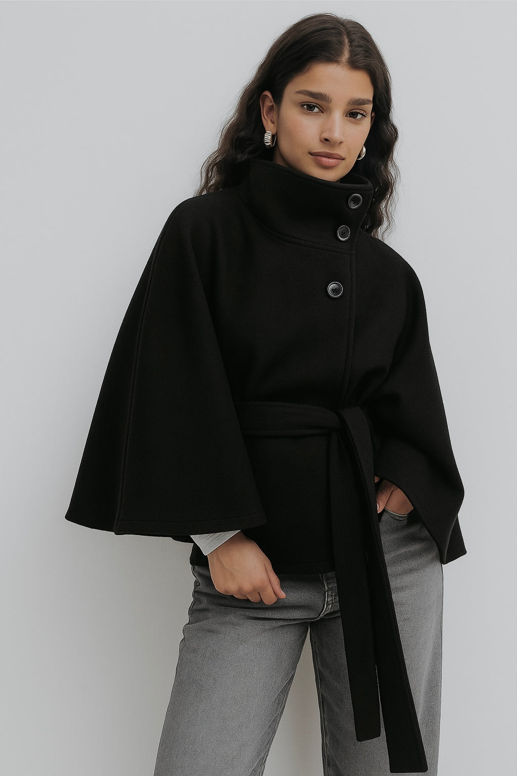 High-Neck Belted Cape Jacket in camel wool blend. Poncho-inspired autumn/winter coat with high-neck collar, cape silhouette and adjustable waist belt. A chic belted jacket combining elegance, comfort and versatile seasonal style.
