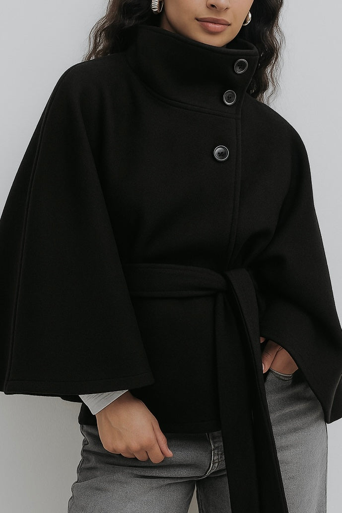 High-Neck Belted Cape Jacket in camel wool blend. Poncho-inspired autumn/winter coat with high-neck collar, cape silhouette and adjustable waist belt. A chic belted jacket combining elegance, comfort and versatile seasonal style.