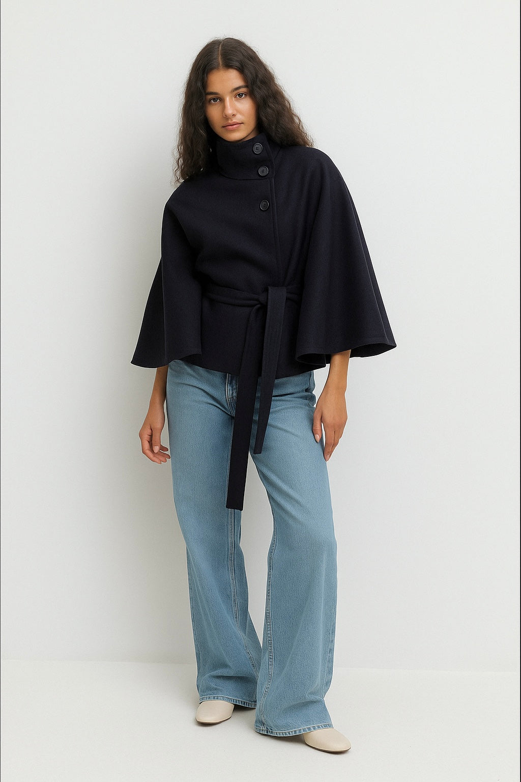 High-Neck Belted Cape Jacket in camel wool blend. Poncho-inspired autumn/winter coat with high-neck collar, cape silhouette and adjustable waist belt. A chic belted jacket combining elegance, comfort and versatile seasonal style.
