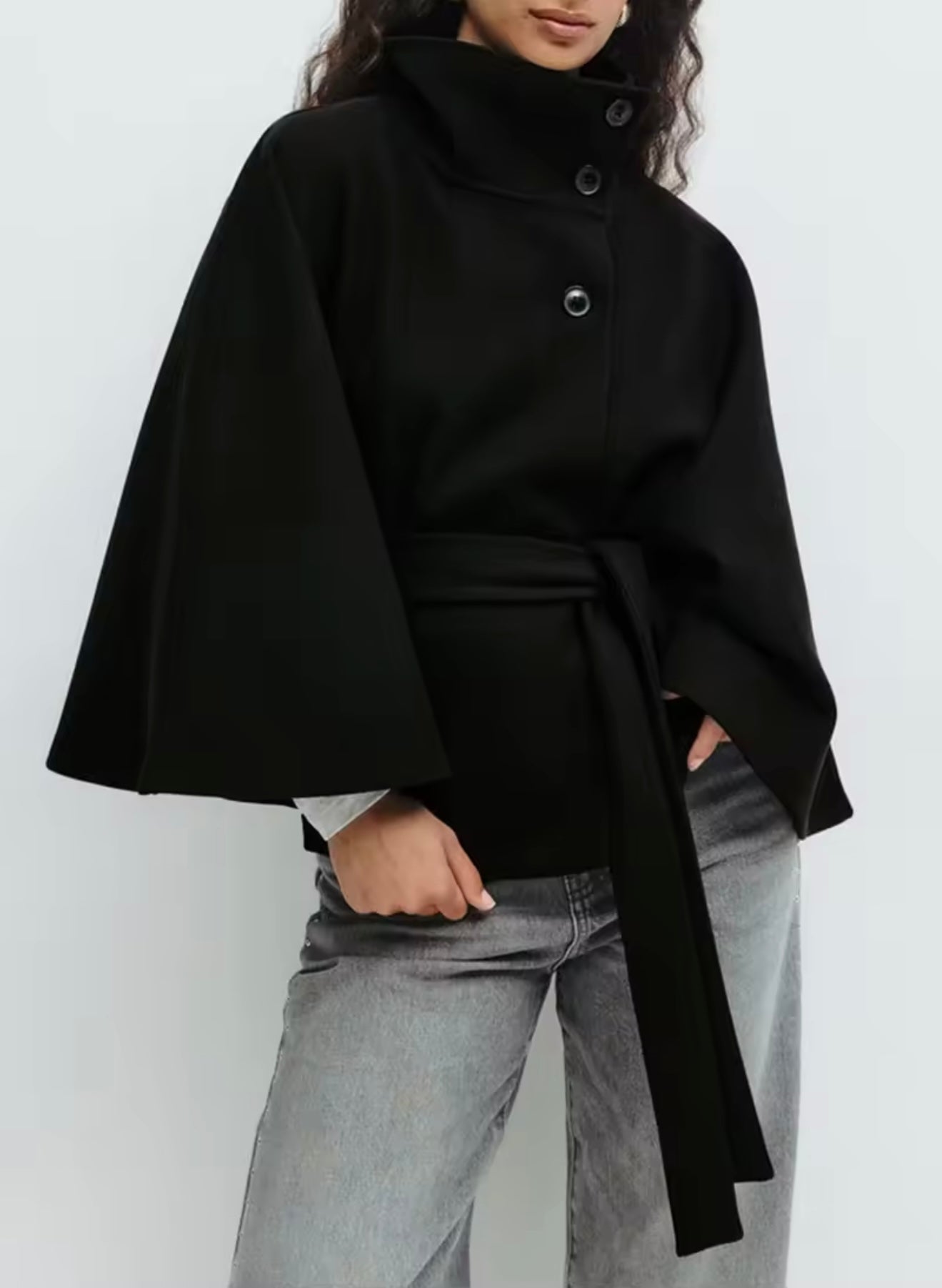 High-Neck Belted Cape Jacket in camel wool blend. Poncho-inspired autumn/winter coat with high-neck collar, cape silhouette and adjustable waist belt. A chic belted jacket combining elegance, comfort and versatile seasonal style.