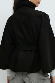 High-Neck Belted Cape Jacket in camel wool blend. Poncho-inspired autumn/winter coat with high-neck collar, cape silhouette and adjustable waist belt. A chic belted jacket combining elegance, comfort and versatile seasonal style.