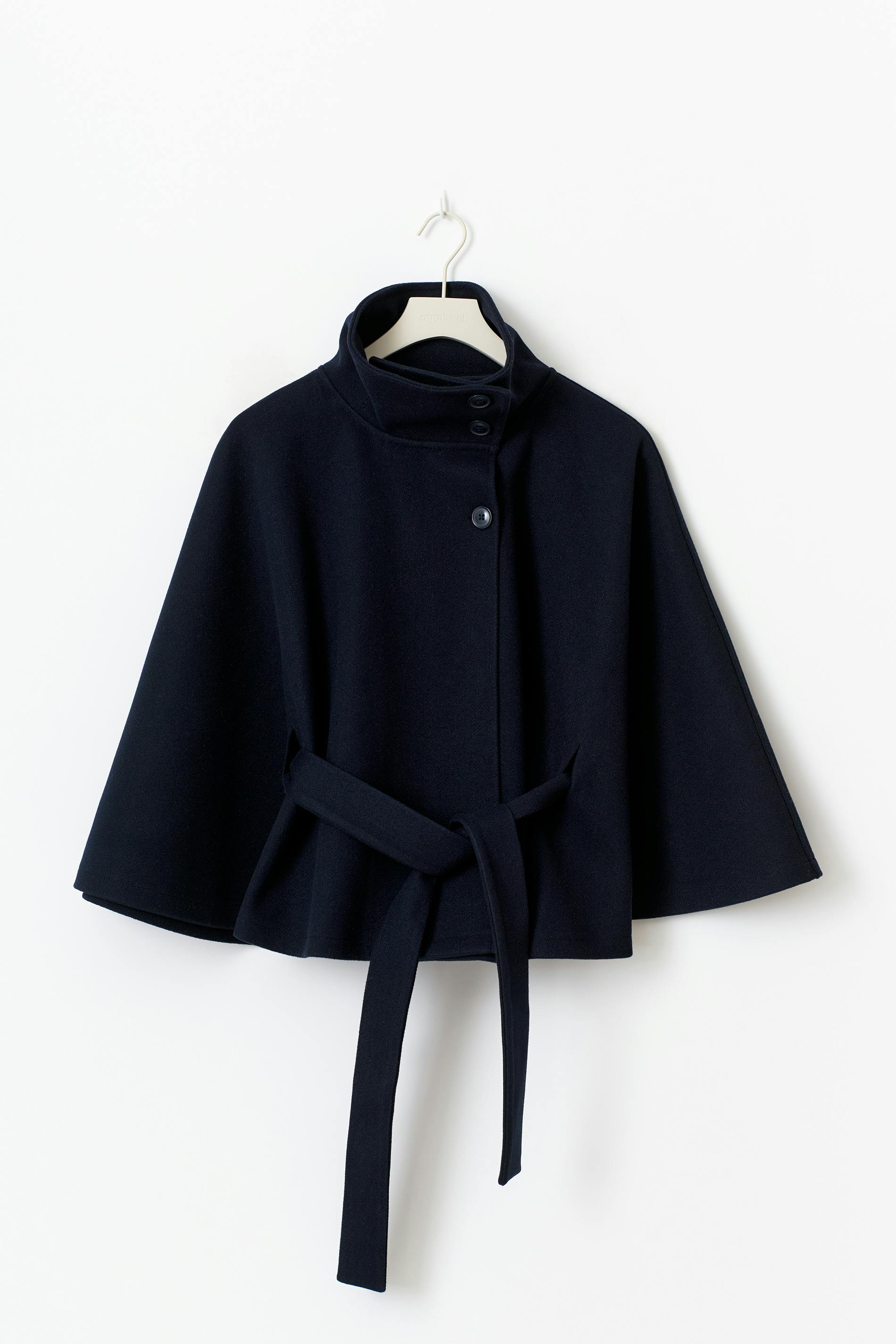 High-Neck Belted Cape Jacket in camel wool blend. Poncho-inspired autumn/winter coat with high-neck collar, cape silhouette and adjustable waist belt. A chic belted jacket combining elegance, comfort and versatile seasonal style.
