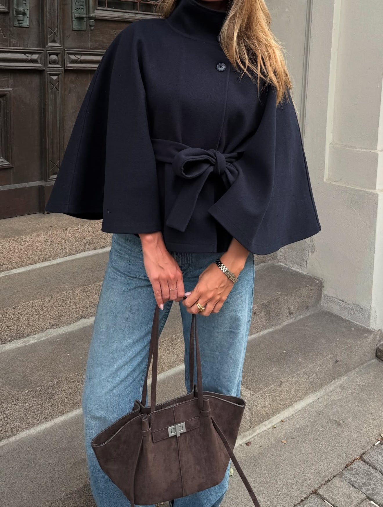High-Neck Belted Cape Jacket in camel wool blend. Poncho-inspired autumn/winter coat with high-neck collar, cape silhouette and adjustable waist belt. A chic belted jacket combining elegance, comfort and versatile seasonal style.