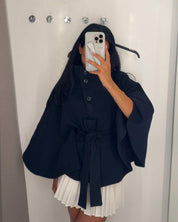 High-Neck Belted Cape Jacket in camel wool blend. Poncho-inspired autumn/winter coat with high-neck collar, cape silhouette and adjustable waist belt. A chic belted jacket combining elegance, comfort and versatile seasonal style.