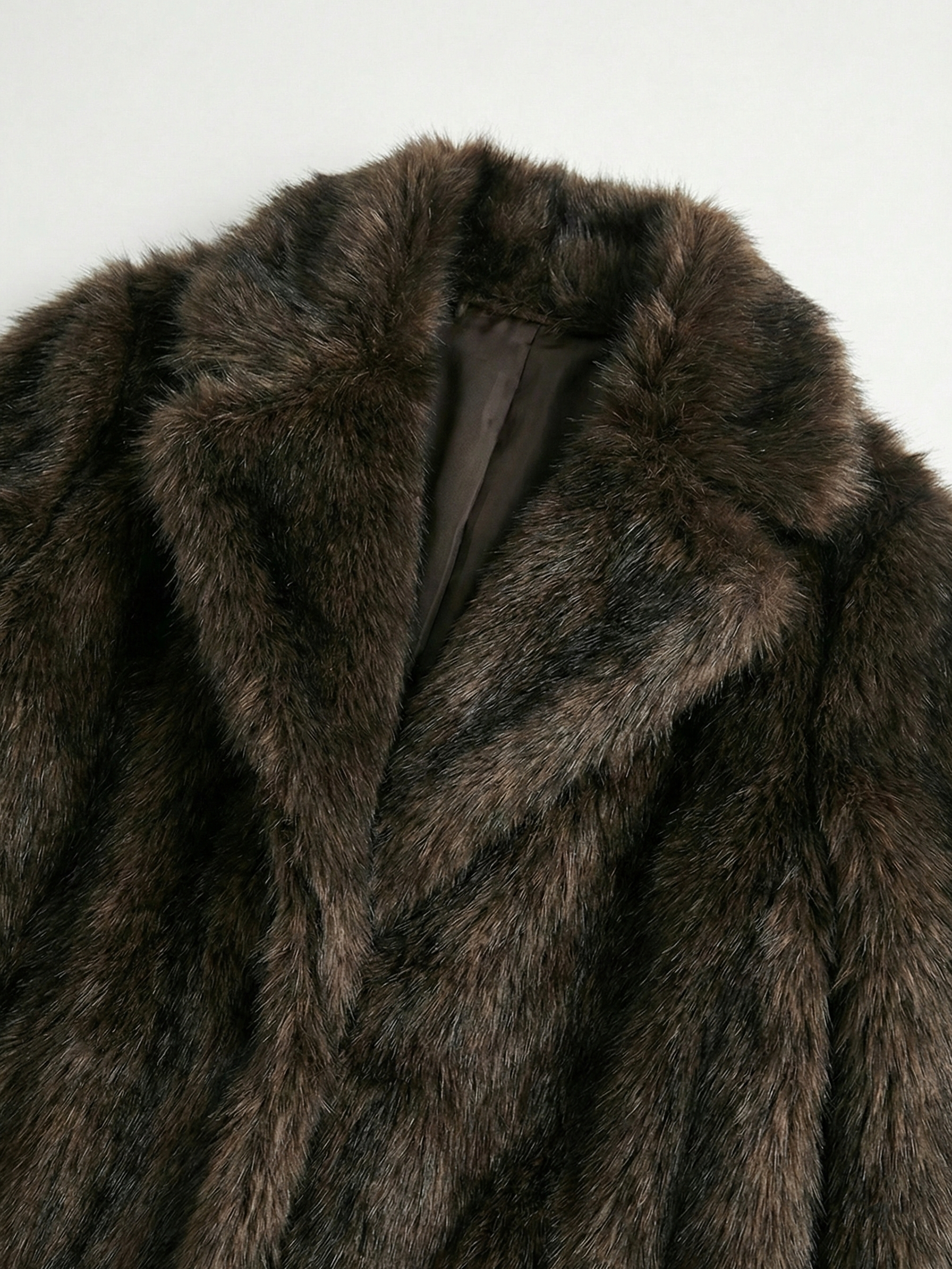 Long faux fur coat in deep brown tones with wide lapel collar and full-length silhouette