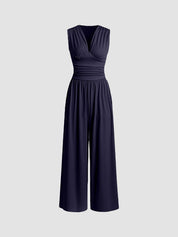 Navy sleeveless jumpsuit with deep V neckline, ruched waist and wide-leg trousers